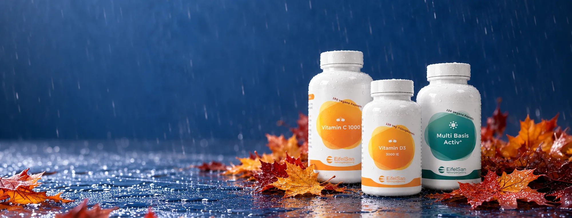 Vitamin C 1000, Vitamin D3 und Multi Basis Aktiv+ auf herbstlichem Laub im Regen